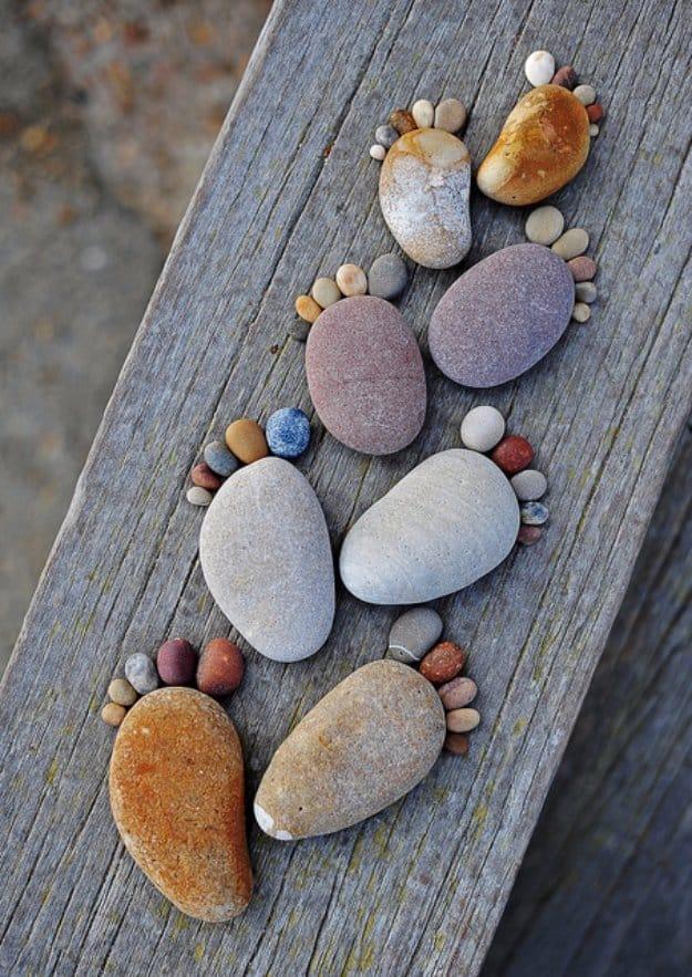 Pairs of footprints made from a large pebble and five small toe stones each, walking along a weathered plank