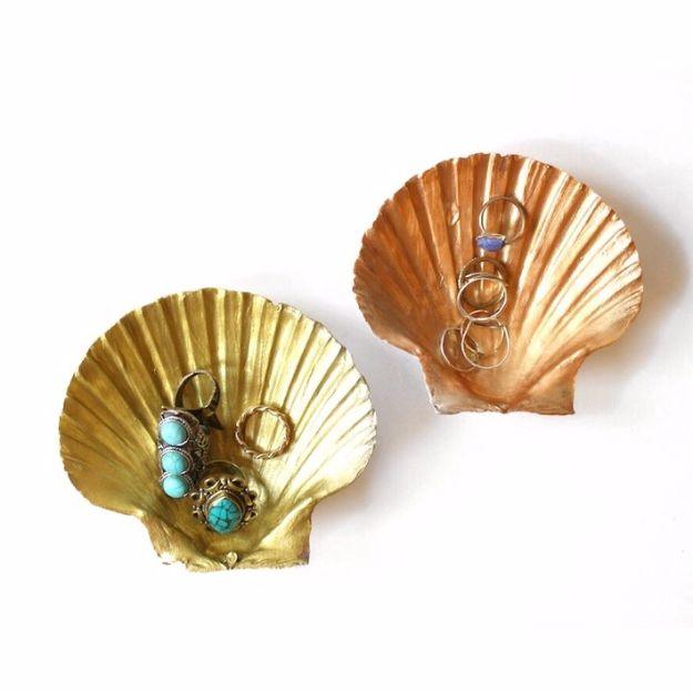 DIY shell ring dish, two scallop shells painted gold and copper inside holding turquoise rings on white