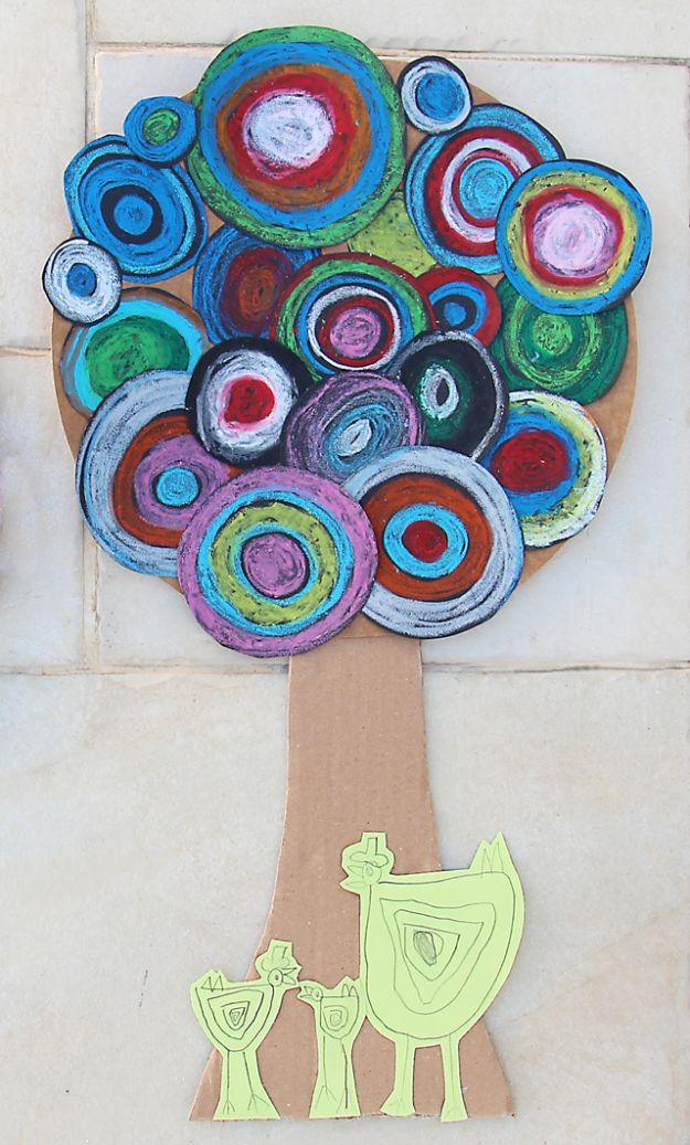 Tree of bright concentric pastel circles on black paper glued to a cardboard trunk, with green birds at the base