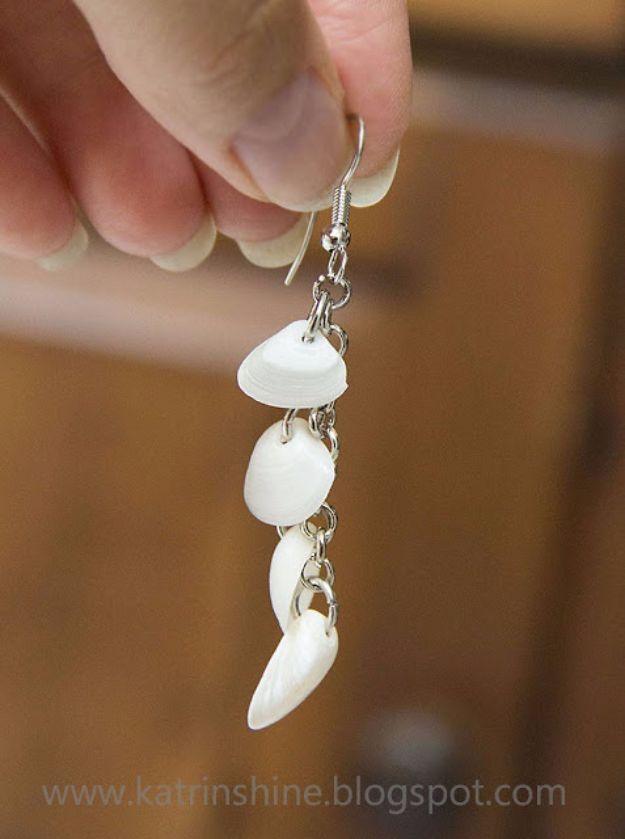 Seashell dangle earrings, a hand holding a fine chain earring hung with small white shells on jump rings