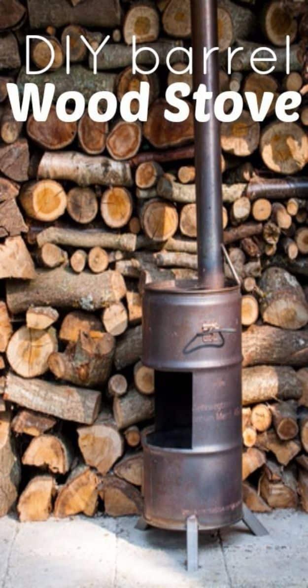 DIY barrel wood stove made from a steel drum with a stovepipe, standing in front of a stacked woodpile outdoors