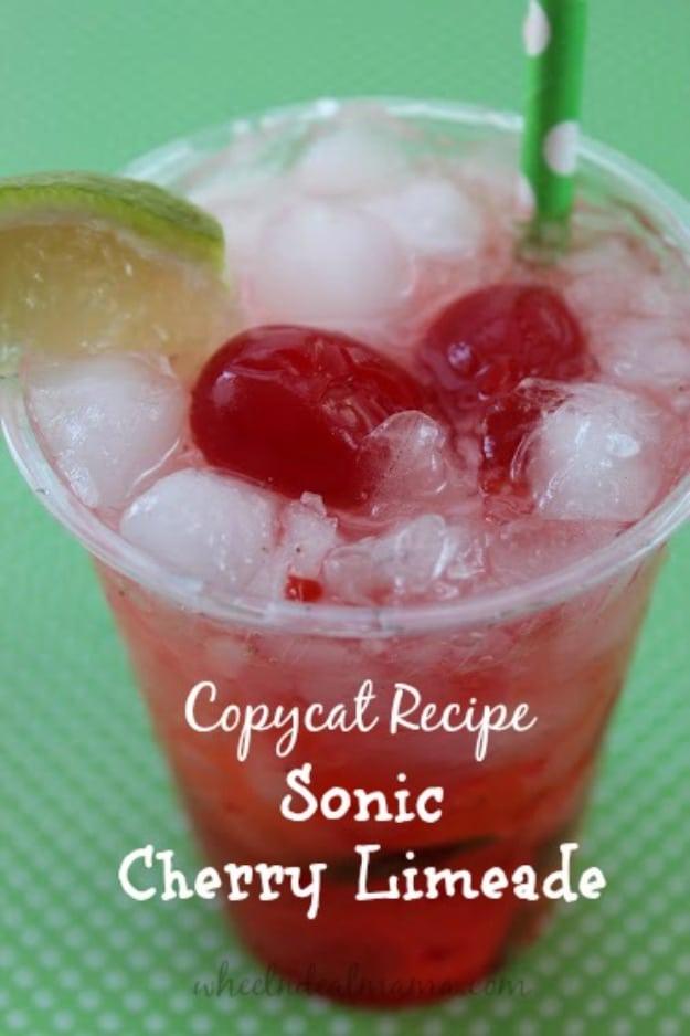 Sonic cherry limeade copycat in a glass with crushed ice, lime wedges, maraschino cherries and a straw