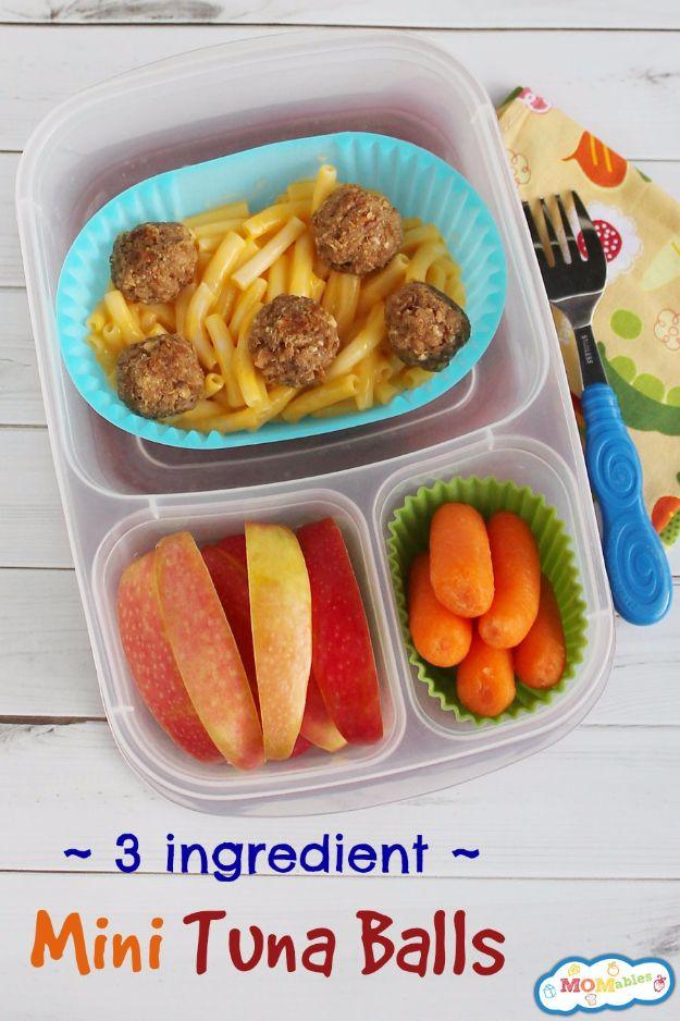 Mini tuna balls packed in a bento lunch box with pasta, apple slices and baby carrots in bright cups