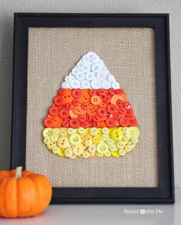 Framed candy corn button art with white, orange and yellow buttons layered on burlap in a black frame