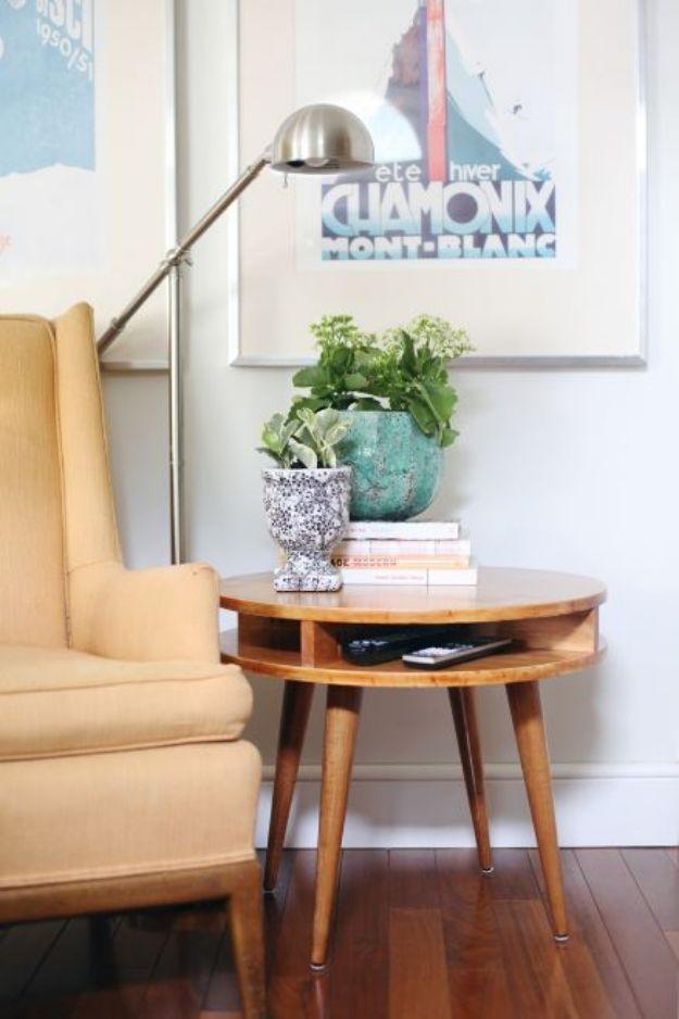 Round honey toned wood side table with open shelf and four tapered legs beside a yellow wing chair and arc floor lamp