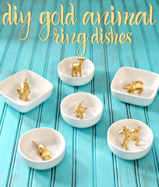 Gold animal ring dishes, six small white bowls each holding a gold spray painted plastic animal on turquoise boards
