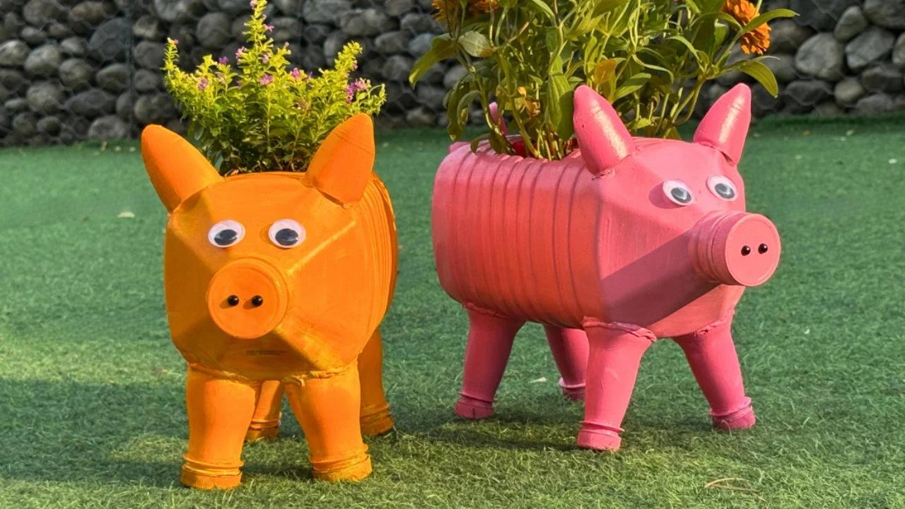 Pink pig planter made from a plastic gallon jug with a snout, ears and curly tail, planted with greenery in a garden