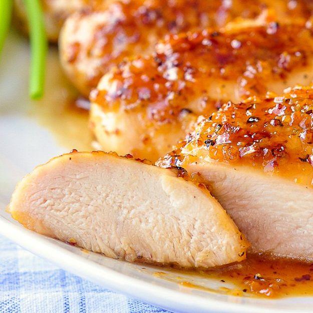 Honey dijon garlic chicken breasts on a white plate under a glossy grainy mustard glaze, one sliced to show the meat