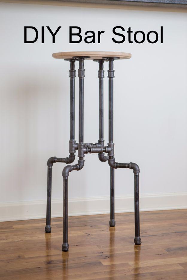 DIY industrial bar stool with a round wood seat on a black half inch pipe base standing against a white wall
