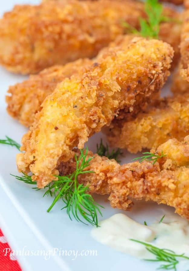 Crispy tilapia sticks fried golden and stacked on a plate with dipping sauce, an easy homemade fish stick recipe