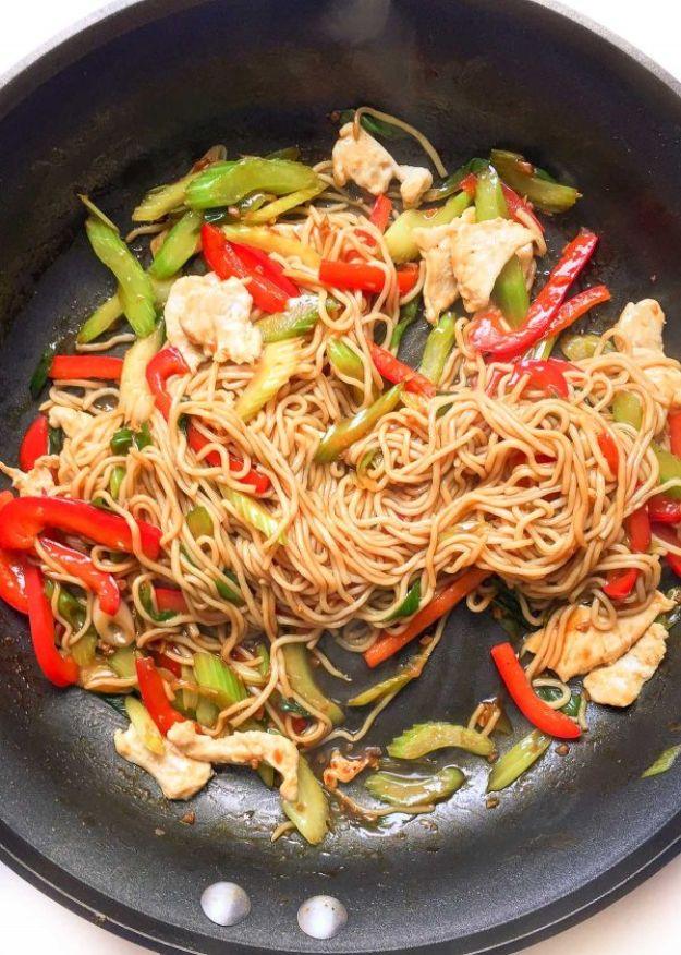 Easy healthy chicken lo mein in a black skillet with noodles, sliced chicken and red and green pepper strips