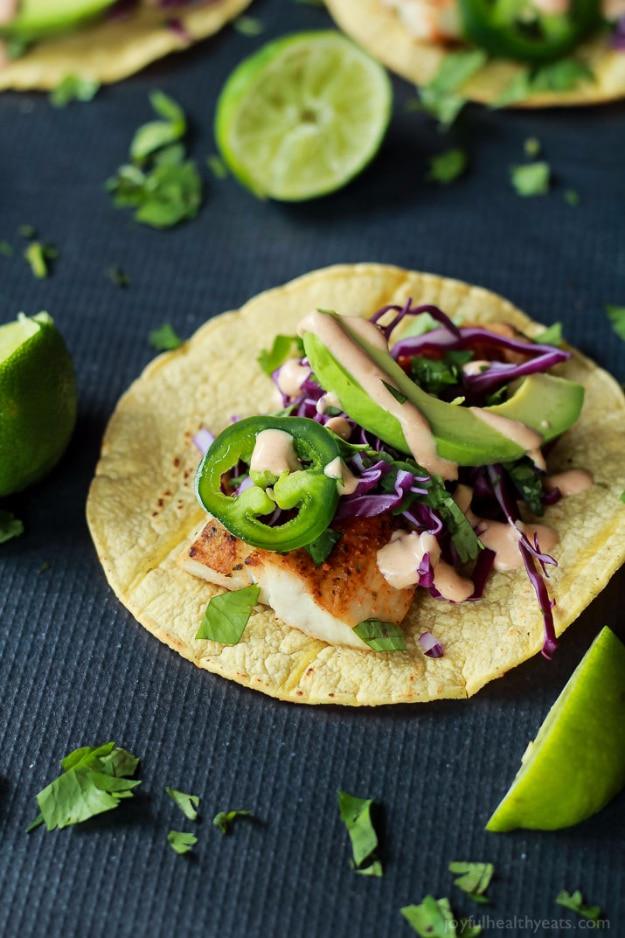Grilled mahi mahi fish tacos in corn tortillas with cabbage slaw, mashed avocado and chipotle crema at a backyard cookout