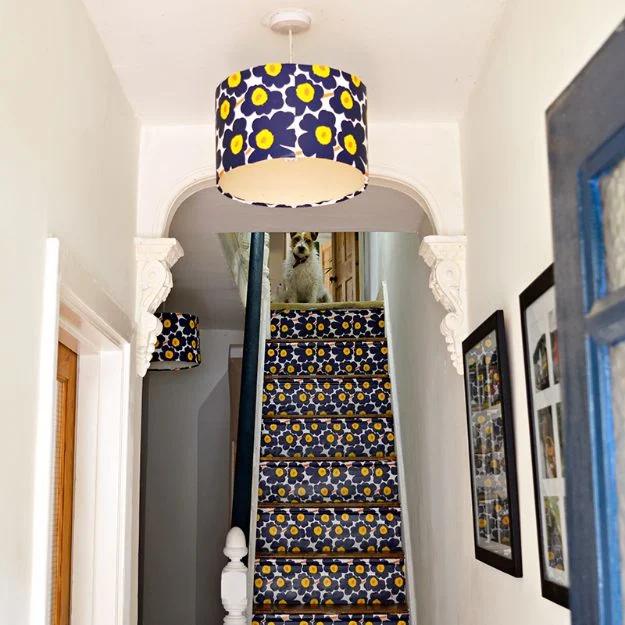 Marimekko stair and lampshade upcycle, a navy and yellow poppy print drum shade above a staircase with papered risers