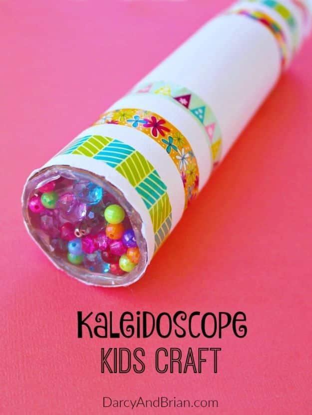 Cardboard tube kaleidoscope covered in patterned washi tape with colored beads visible in the end, on hot pink