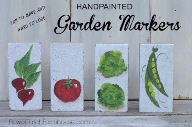 Four pale concrete bricks hand painted with radishes, a tomato, lettuce and peas under a Garden Markers title
