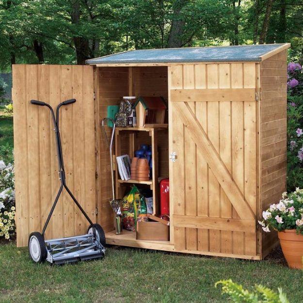 Little tool shed, a small pale cedar shed with both doors open showing shelves and tools, and a push mower standing in front