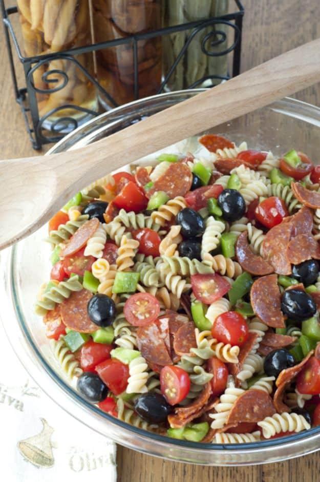 Classic Italian pasta salad with rotini, pepperoni, black olives and cherry tomatoes in a large glass bowl