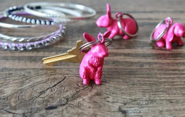 Plastic bunny key chain, a bright pink painted plastic bunny on a key ring with bangles on weathered wood