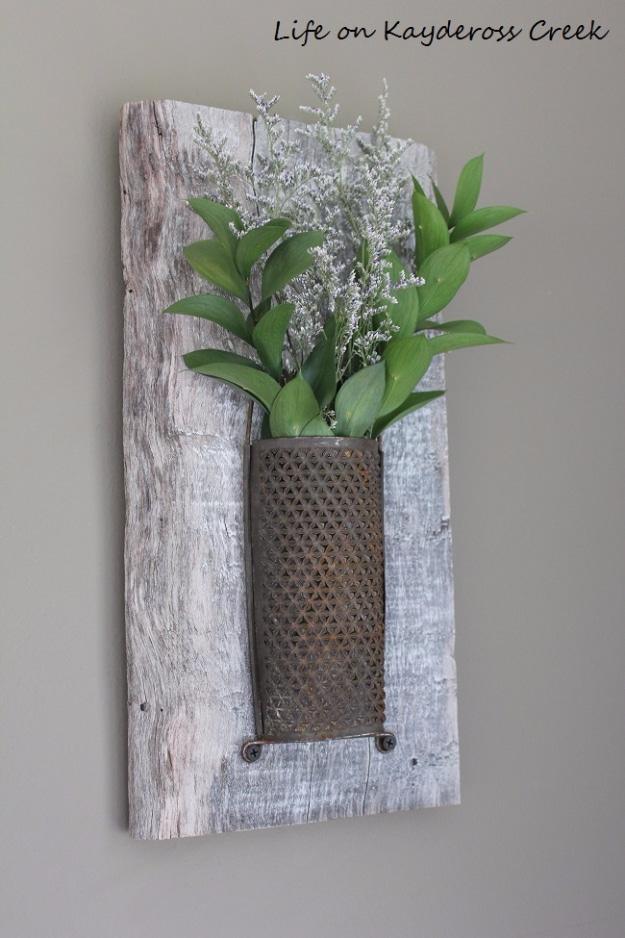 Rustic bedroom wall decor, a rusty metal grater screwed to a gray weathered board holding dried flowers and greenery