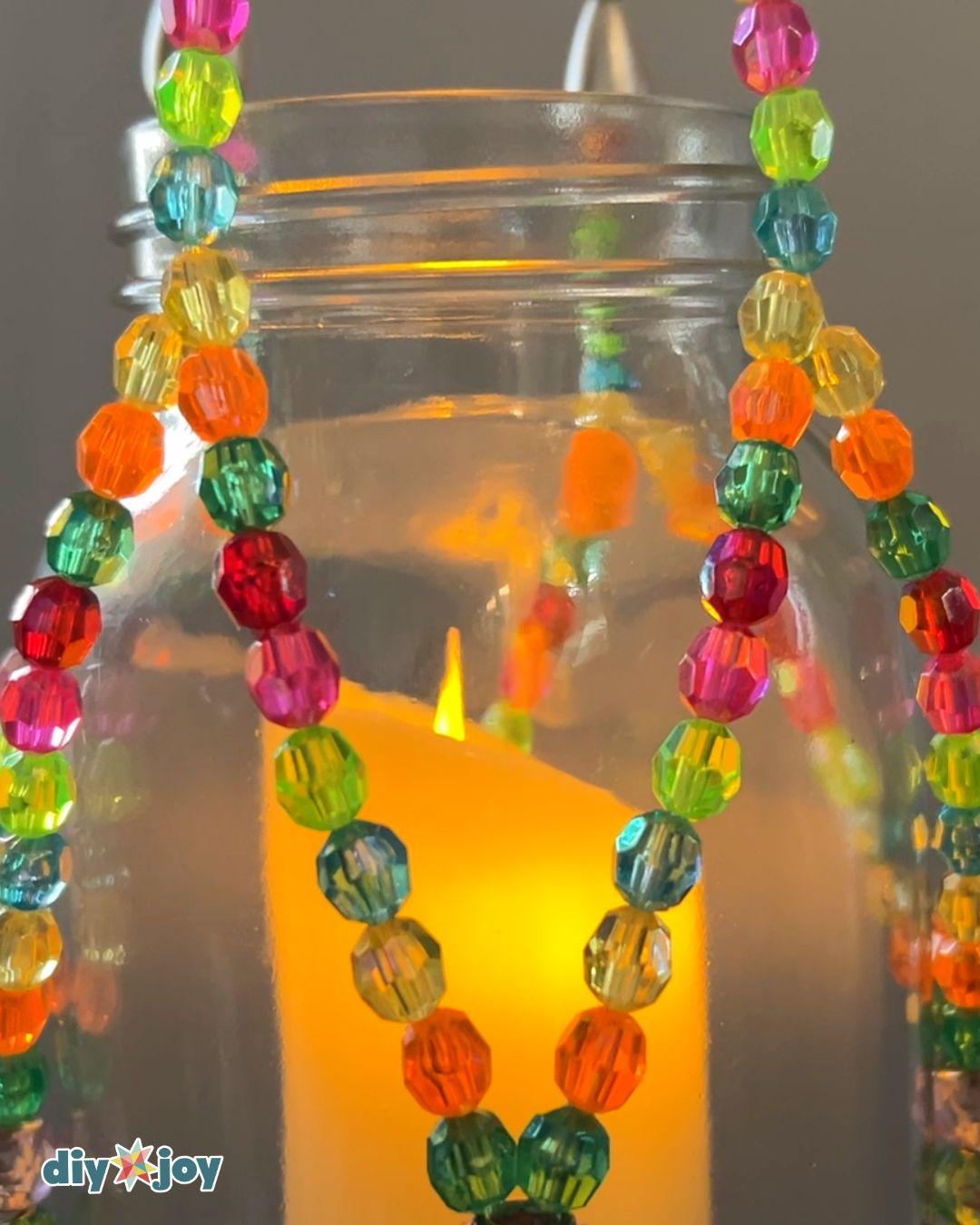How to make a beaded lantern, showing threads gathered through a small wooden ring and held down with painter's tape