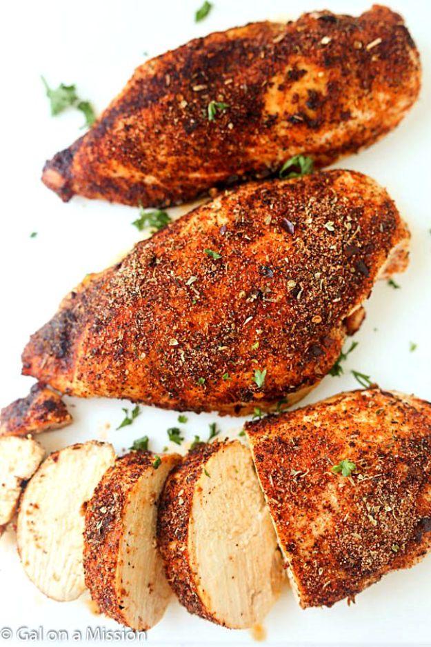 Cajun style baked chicken breasts under a dark red spice rub on a white plate, one breast sliced into thick pieces