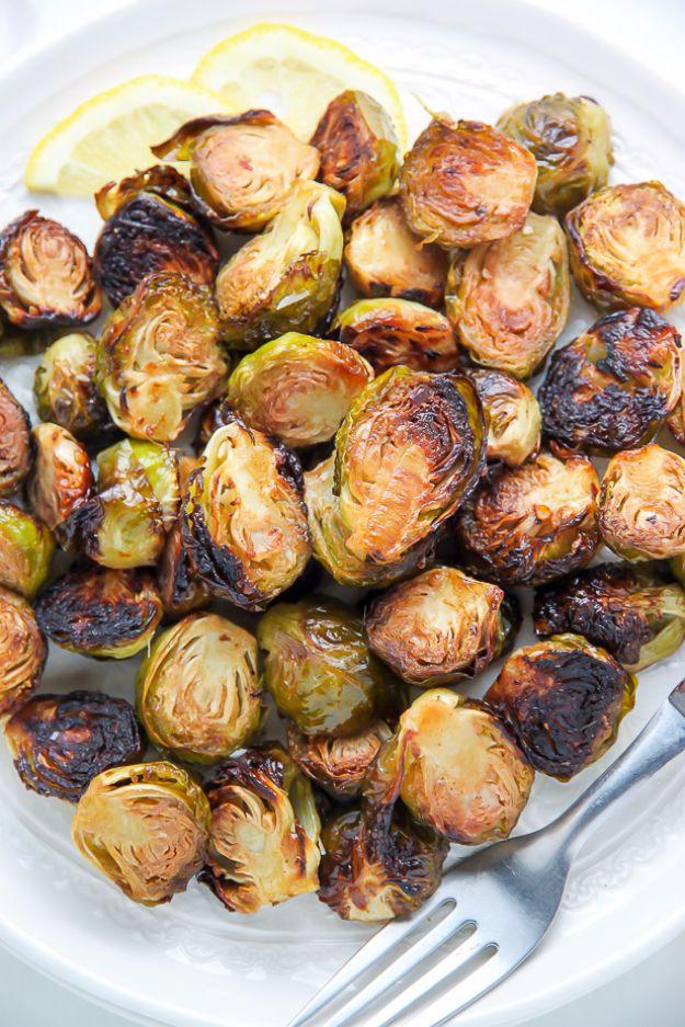 Lemon and garlic roasted brussels sprouts browned deeply on a white plate with two thin lemon slices