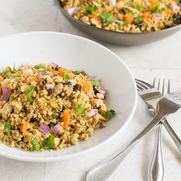 Tofu mushroom quinoa scramble with golden crumbled tofu, portobello mushrooms and grated carrot in a pan