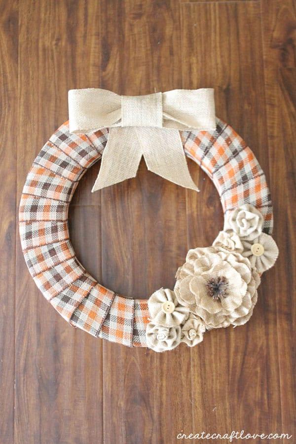 Burlap and plaid ribbon wreath with the plaid layered on top of the burlap, a cozy autumn door wreath