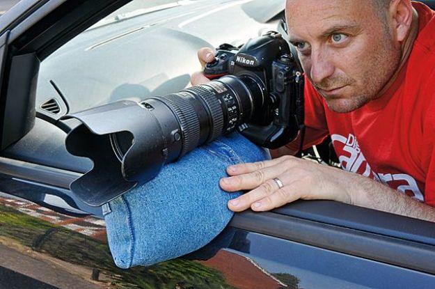 Reduce camera shake, a man leaning from a car window resting a telephoto lens on a blue beanbag on the door
