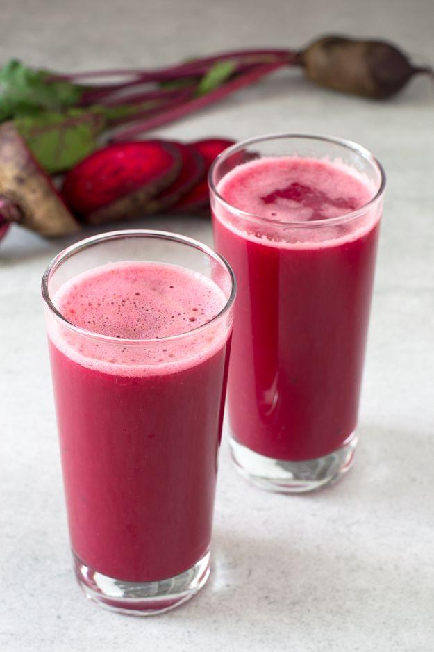 Glowing skin juice in two glasses, deep pink from the beetroot, with whole beets and their stalks behind
