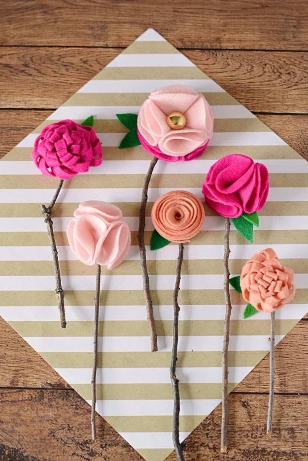 Felt petals in coral and cream glued around bare twig stems, gathered into a clear glass jar by a window