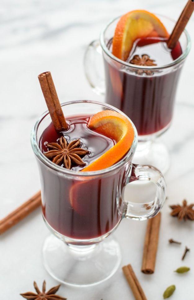 Two glass mugs of hot slow cooker spiced wine garnished with orange slices, star anise and cinnamon sticks