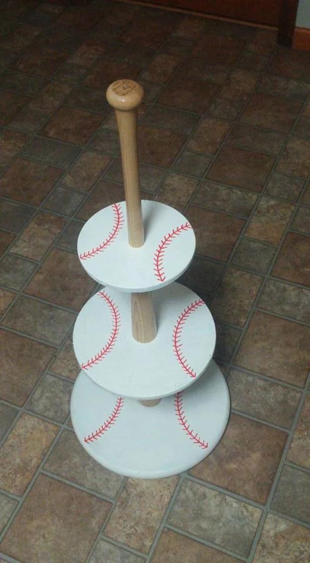 Three tier cupcake stand of white rounds painted with red baseball stitching, stacked on softball bat sections