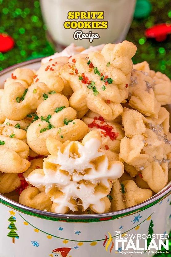 A holiday tin heaped with buttery spritz cookies in wreath, tree and star shapes with red and green sugar and white chocolate