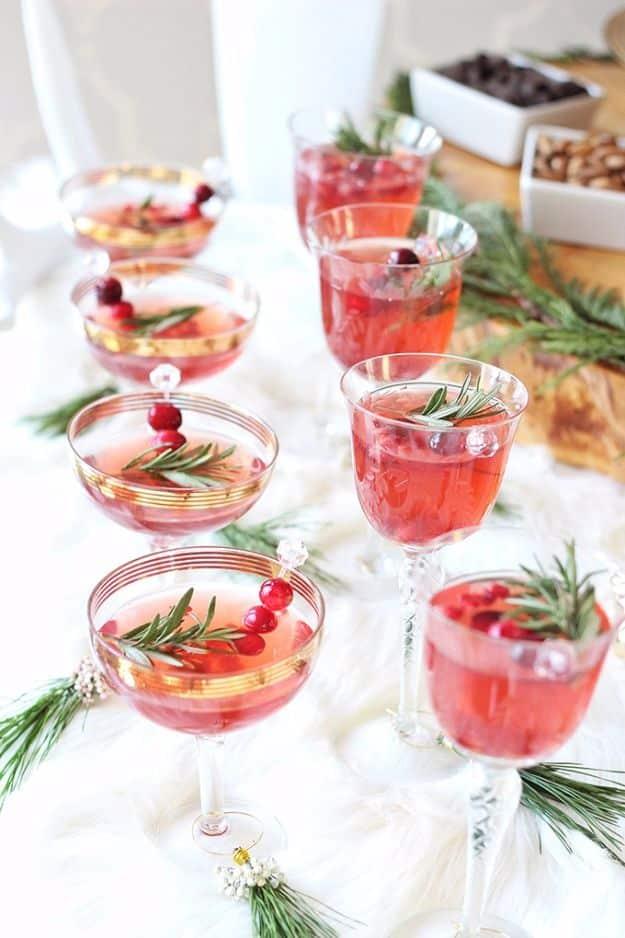 Coupe glasses of sparkling pomegranate cranberry sangria garnished with fresh cranberries and rosemary sprigs