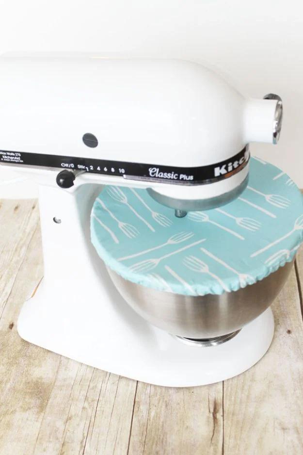 A quilting cotton mixer bowl cover with elastic in the casing, stretched over a stand mixer on a counter.