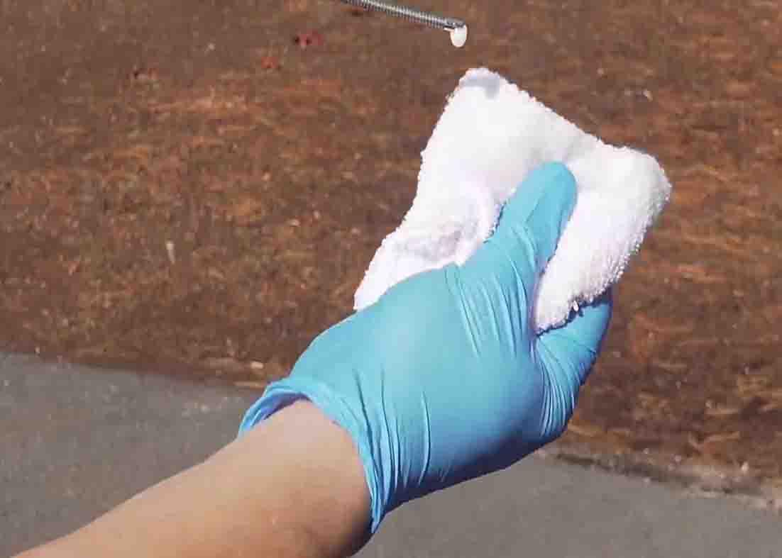 Soaking the rag with WD-40 to clean the windshield wiper blades