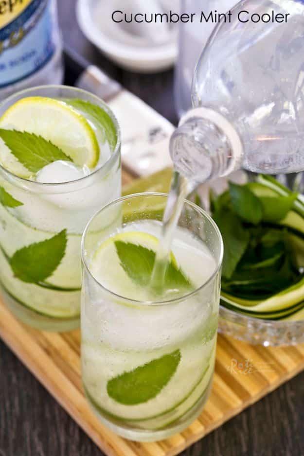 Cucumber mint cooler with curled cucumber ribbons, mint and lime as sparkling water is poured over ice