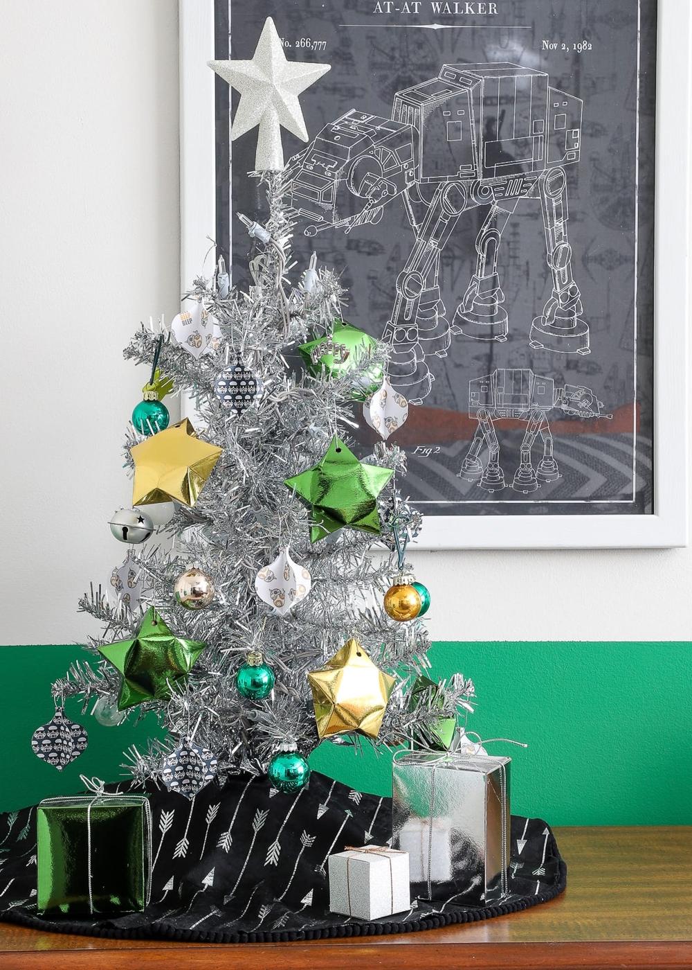 Nine faceted foil paper star ornaments in red, green, gold, blue and teal scattered on a pale gray background