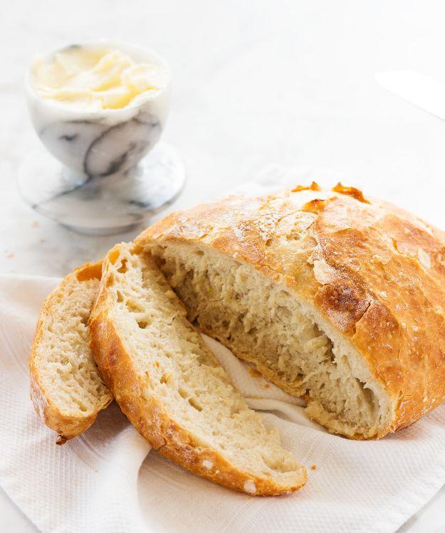 No knead artisan bread baked in a cast iron Dutch oven with a crackled rustic crust and a floury top