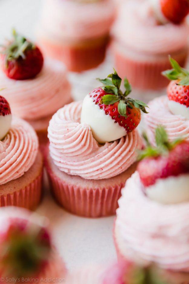 White chocolate strawberry cupcakes with pink buttercream swirls topped with white chocolate dipped berries
