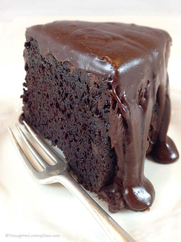 Brick street chocolate cake slice on a white plate with thick fudgy cocoa icing running down the sides