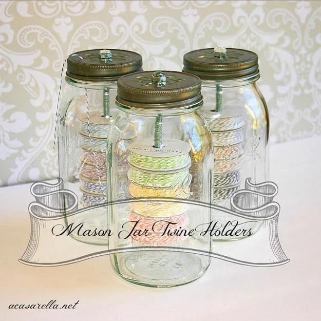 Three tall mason jars with daisy cut out lids holding stacked spools of colored twine, threads pulled through the lids