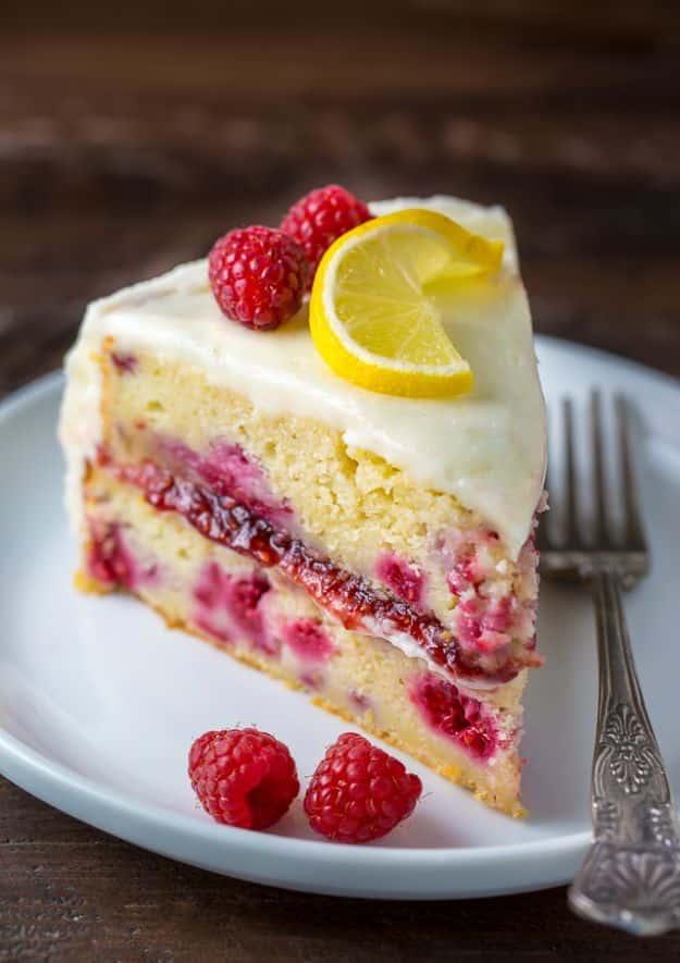 Lemon layer cake with raspberry filling and pink buttercream topped with fresh raspberries, a homemade birthday cake recipe
