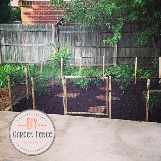 DIY garden fence, black plastic netting stretched on wooden stakes around a raised garden bed with a small framed door