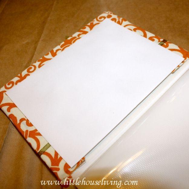Plain photo album covered in orange and cream patterned fabric, lying open on a tan surface being wrapped