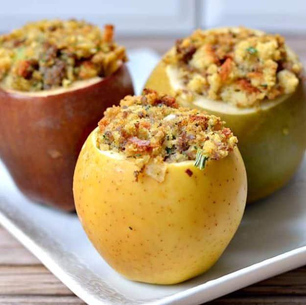 Baked apples hollowed out and filled with savory sausage stuffing, browned on top in a white baking dish