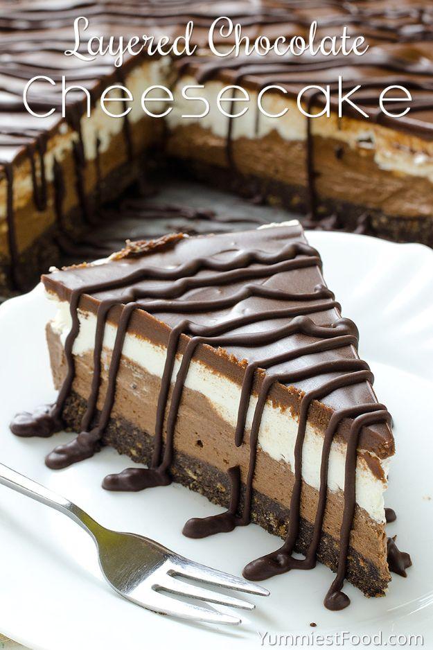 Layered chocolate cheesecake slice on a white plate, chocolate drizzle over the dark and light no bake layers