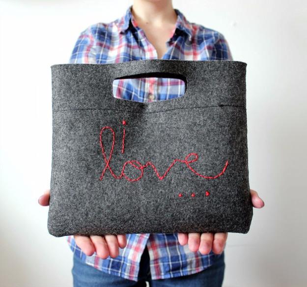 Charcoal wool felt clutch with a cut out slot handle and the words i love embroidered in thick red thread