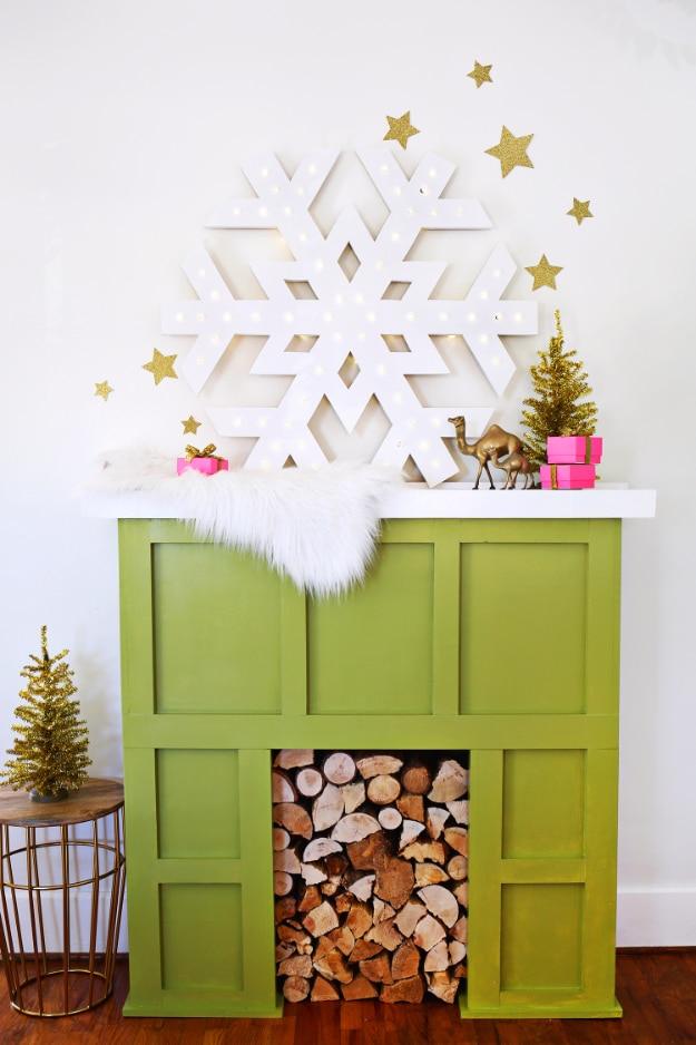 White marquee snowflake studded with small lights, hung above a green faux fireplace with gold glitter stars